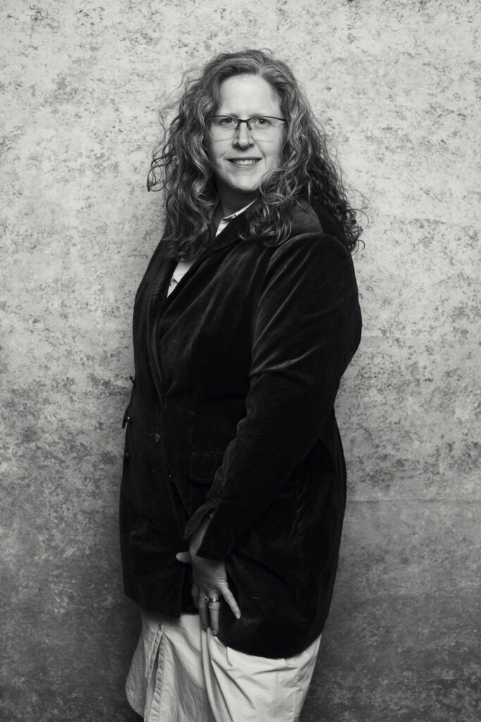 black and white image of Jennifer in front of a painted studio background