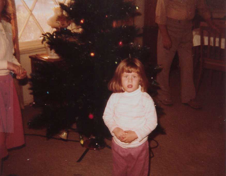 Jennifer stands in front of tree as a child.