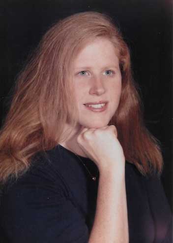 Jennifer rests chin on hand while looking off to camera right. Studio portrait for college yearbook.